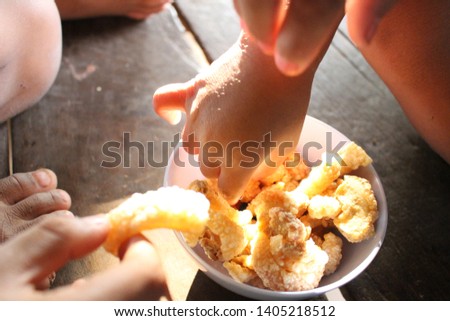 Children pick up the fried pork in the cup on the table, take a blurred picture