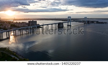 A cloudy Fort Totten golden sunset in Queens New York with the sky and the Throgs Neck Bridge Reflecting onto the water