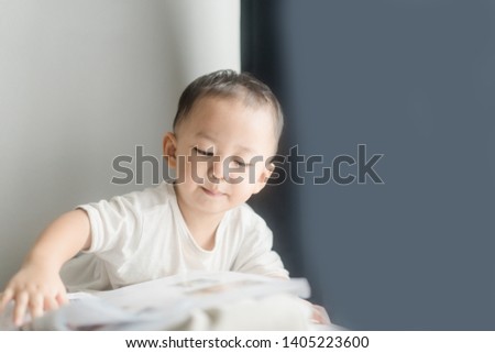 2 years little asian toddler boy in white t-shirt reading bible picture story for kid in the morning.Hands holding on a Holy Bible in bed room concept for Education bible study, faith and religion.