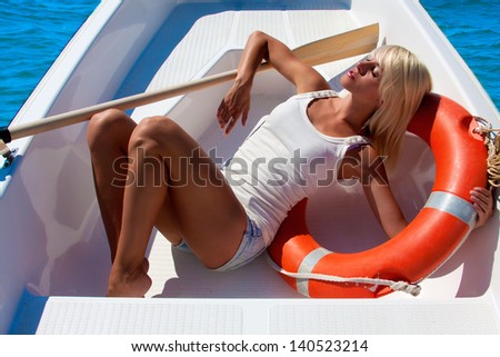 Beautiful girl is drifting on the sea in a lifeboat