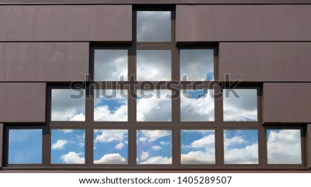 Detail of a modern facade with a large triangular window made up of small squares that reflect the sky. Background and texture. Copy space