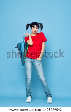  young woman in red t-shirt holding an umbrella on a blue background                             