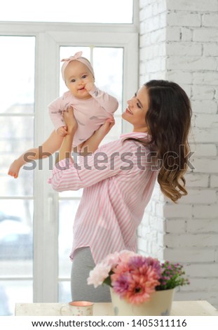 Mom and 8-month-old baby hugging on the bed in pink clothes