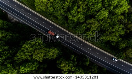 Long highway through the green forest. Photo from above makes by dron