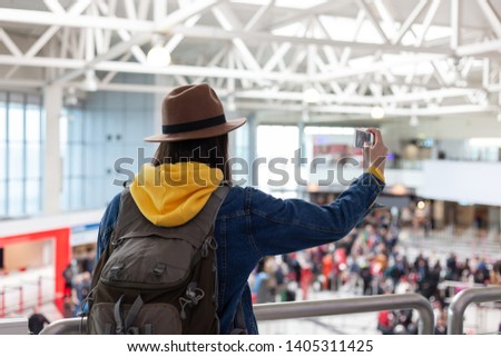 Vacation Selfie. Beautiful young woman in hat and jeans jacket taking selfie while waiting for boarding in the airport.