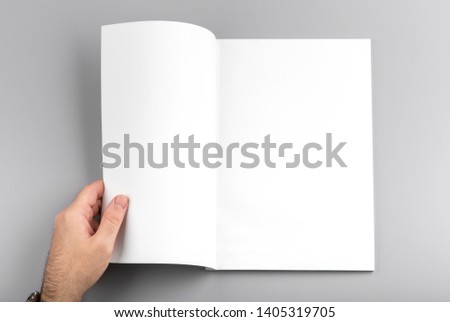 Photo. Man holds open journal. For graphic designers presentations and portfolios. Mock up of empty magazine. Blank book mockup isolated on gray background.