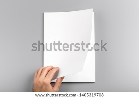 Photo. Man holds open journal. For graphic designers presentations and portfolios. Mock up of empty magazine. Blank book mockup isolated on gray background.
