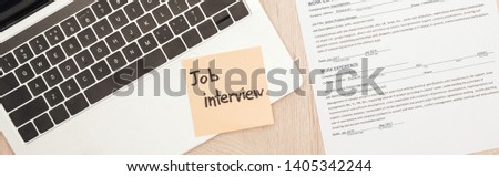 panoramic shot of laptop, resume template and sticky note with job interview lettering on wooden table