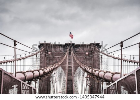 Huge dramatic landscape of the architecture of the famous Brooklyn Bridge in New York City under a contrasting stormy sky