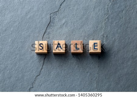 SALE the word on small wooden blocks on a dark grey slate background