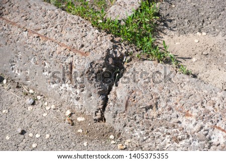 Destroyed concrete curb on an asphalt road, city shot in the summer on a sunny day close-up