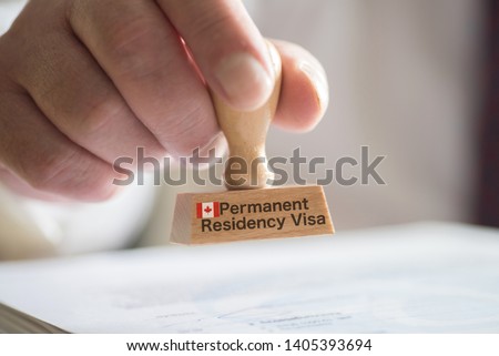 A man and a stamp for a visa for Canada Royalty-Free Stock Photo #1405393694