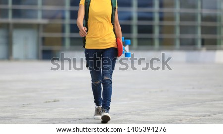 woman skateboarder walking with skateboard in hand at city