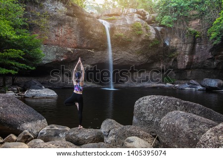 Young girl asian women is playing  yoga in front of the waterfall.
