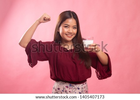 Healthy Asian woman drinking a glass of milk on pink background