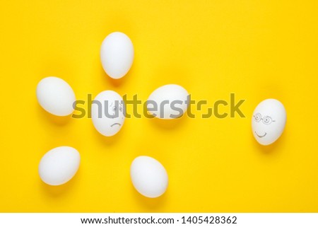 Bullying concept with eggs on yellow background. Top view, minimalism