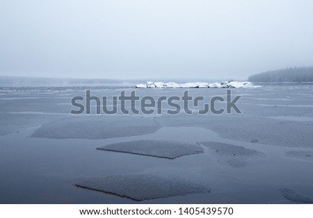 Partly frozen lake on a misty day