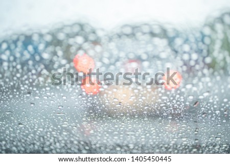 Spot focus  Drops of rain flowing into the car glass At the time of rain Blurred background as a car taillight.