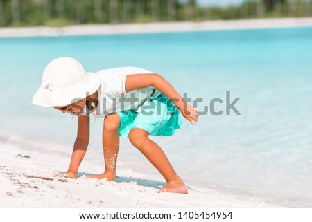 Little adorable girl drawing picture on white beach