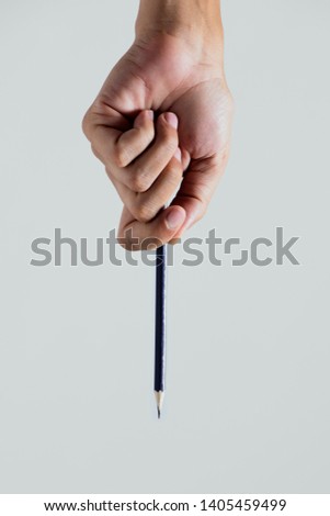 closeup of a young caucasian left-hander man with a sharpen pencil in his hand, upside down, against an off-white background Royalty-Free Stock Photo #1405459499