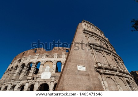 A day time picture of an oval amphitheater in the center of the city of Rome, Italy with blue sky and no people.