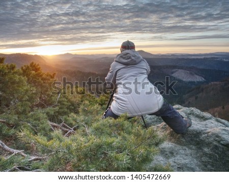 Photographer taking picture. Woman artist photo enthusiast stay with camera above valley and works. Nice view over dried trees in valley.