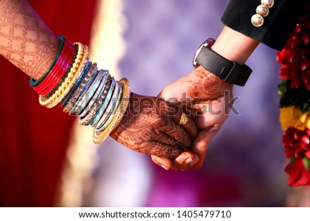 An Indian bride and groom holding their hands with ring during a Hindu wedding
