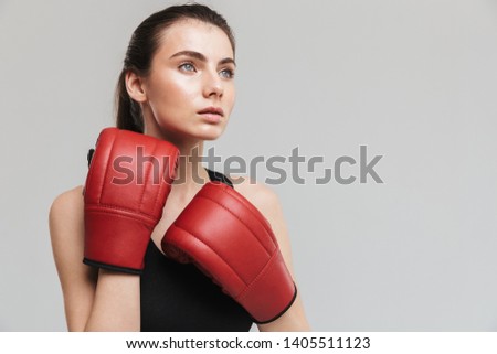 Image of a beautiful young sport fitness woman boxer isolated over grey wall background make exercises in gloves.