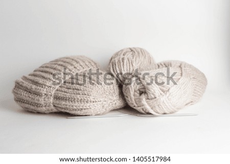 Wool yarn in rolls, a ball of wool and a handmade knitted hat in a basket