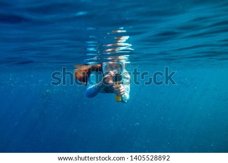 Woman making photo underwater. Girl snorkeling in full-face mask. Snorkel with fish under water surface. Snorkeling gear. Action camera. Active vacation by tropical seaside. Diving girl in open water Royalty-Free Stock Photo #1405528892