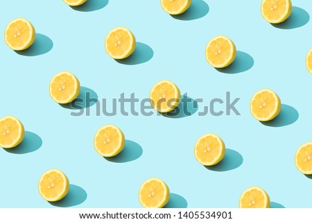 Trendy sunlight Summer pattern made with yellow lemon slice on bright light blue background. Minimal summer concept. Royalty-Free Stock Photo #1405534901