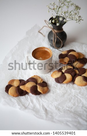 Two color cookies and a cup of coffee on the white table 