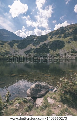 mountain lake panorama view in late summer in Slovakian Carpathian Tatra with reflections of rocky hills in water. Rohacske plesa lakes near Zverovka village. - vintage old film look