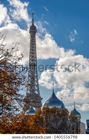 Domes of the Holy Trinity Russian Orthodox Cathedral with Eiffel tower in background. Autumn trees on foreground. Paris, France 