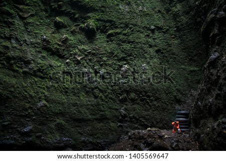  Widodaren Cave in Bromo Tengger Semeru National Park, East Java, Indonesia. Photographer taking picture of green plant on the wall. 