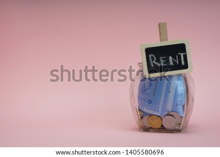'Rent' written at small blackboard with jar loaded with money