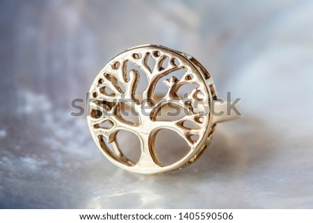Brass metal ring in shape of treein mandala on pearl background