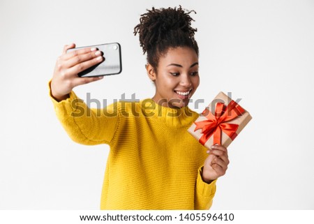 Image closeup of excited african american woman taking selfie photo with gift box isolated over white background