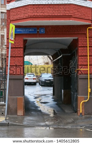 Arch of the red brick house in Moscow. Blue address plaque with russian text: Sivtsev Vrazhek pereulok, house number 12.