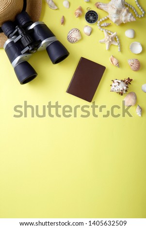 Flat lay traveler accessories on yellow background with shellfish, binoculars and straw hat. Top view travel or vacation concept. Summer background.