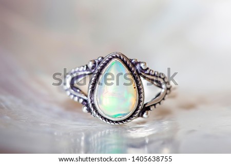 Silver ring with opal mineral gemstone on pearl background