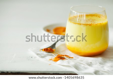Healthy ayurvedic drink golden almond milk or pumpkin turmeric latte with curcuma powder on white background close-up copy space.Trendy Asian natural detox beverage with spices for vegans