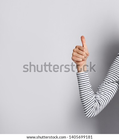 Female hand in a striped sweater with thumb up.