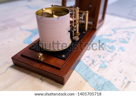 Vintage marine barograph with opened cover standing on a navigational chart Royalty-Free Stock Photo #1405705718