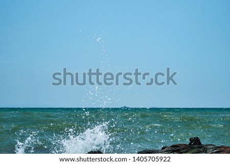 Image of the sea shore. In the background is a warship.