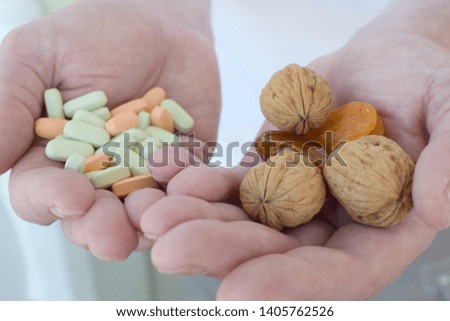 A person holds in one hand capsules with dietary supplements and in the other walnuts and dried fruits. The concept of choosing between pills and a healthy diet. Healthy lifestyle
