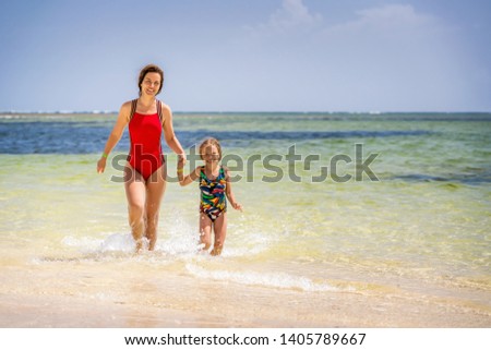 Young mother and little daughter running on the beach in Dominican Republic