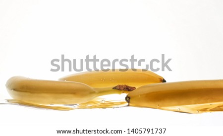 Closeup photo of fresh ripe bananas falling and splashing in water against white isolated background