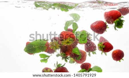 Closeup beautiful photo of lots of fresh raspberries and mint leaves flating in clear water