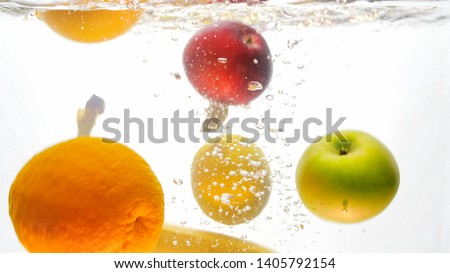 Closeup isolated photo of fresh ripe apples, bananas and oranges falling and splashing in water